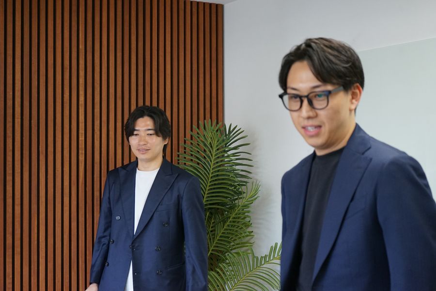 オフィスで立ったまま話す株式会社Remindのメンバー2名